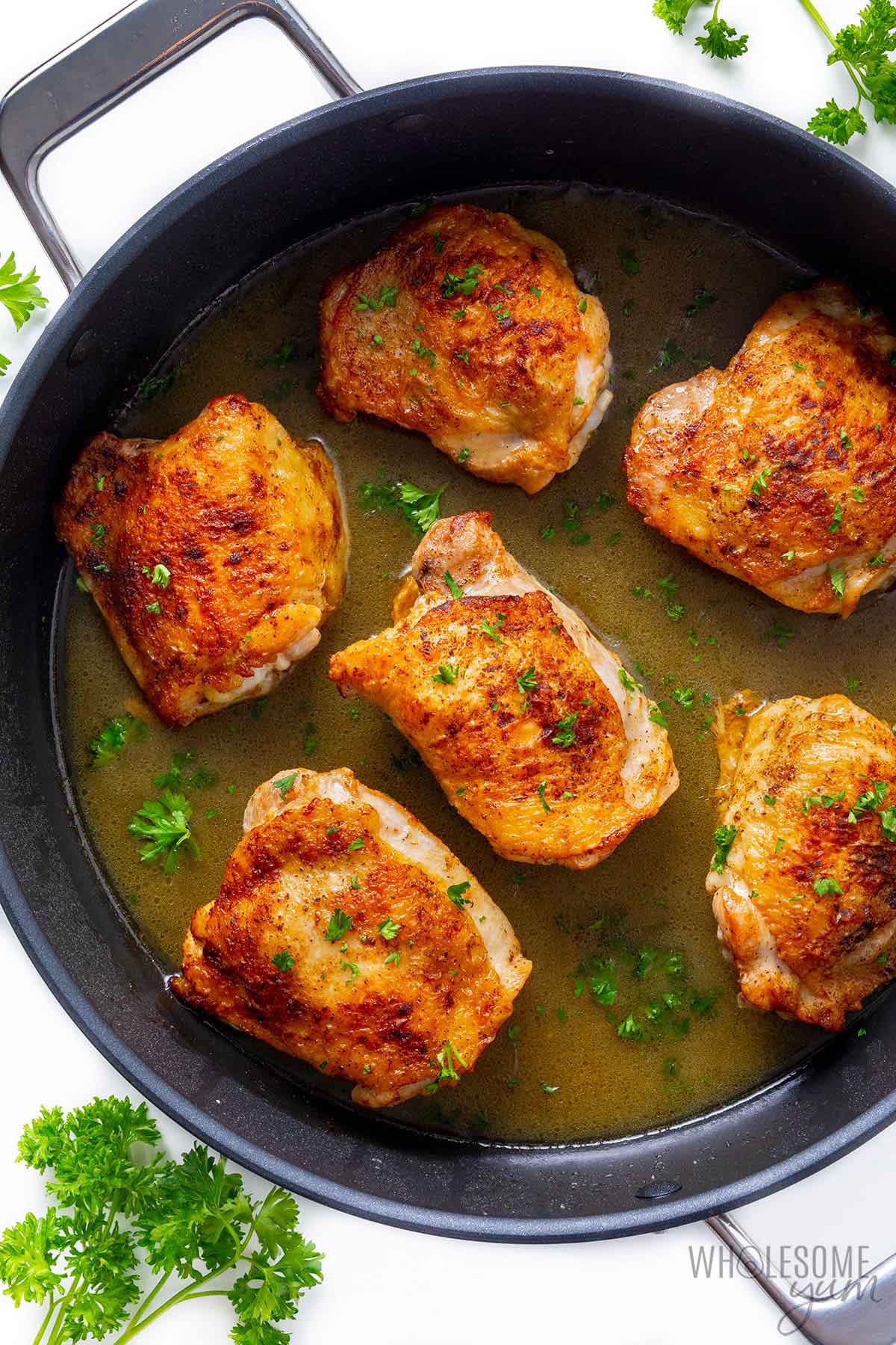 Frying chicken thighs in a pan.