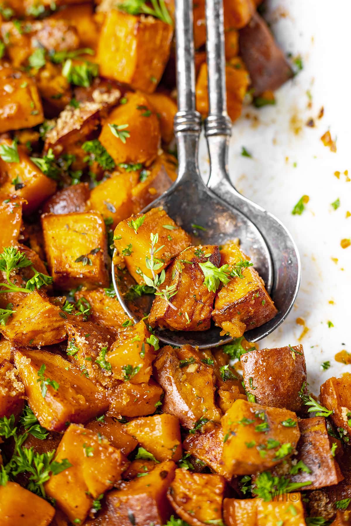 Roasted sweet potatoes on a plate with a spoon. 