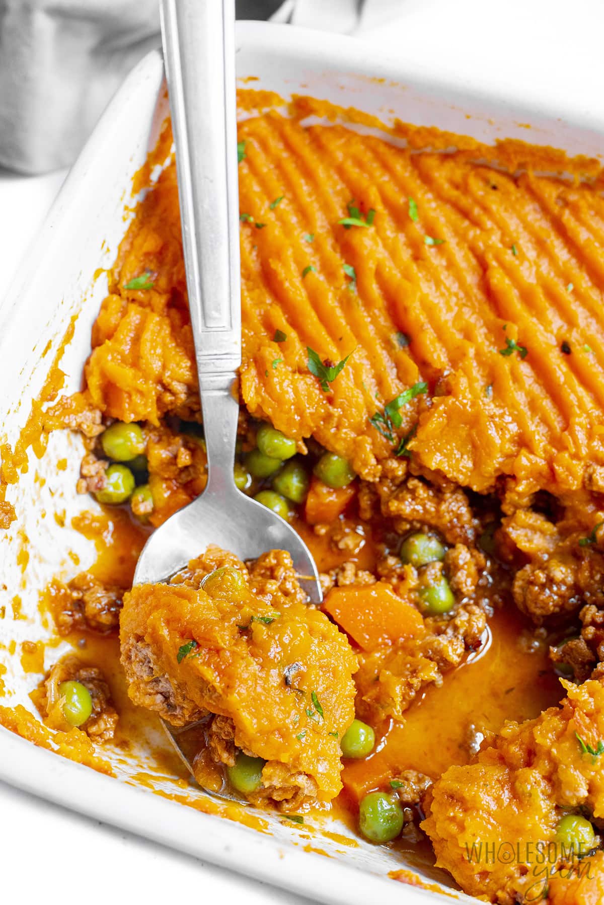 Baked shepherd's pie with sweet potatoes in a dish with a serving spoon.