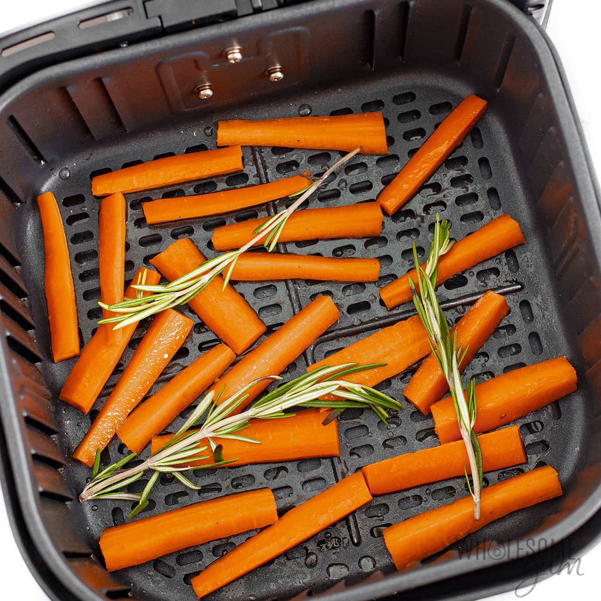 Seasoned carrots in an air fryer basket.
