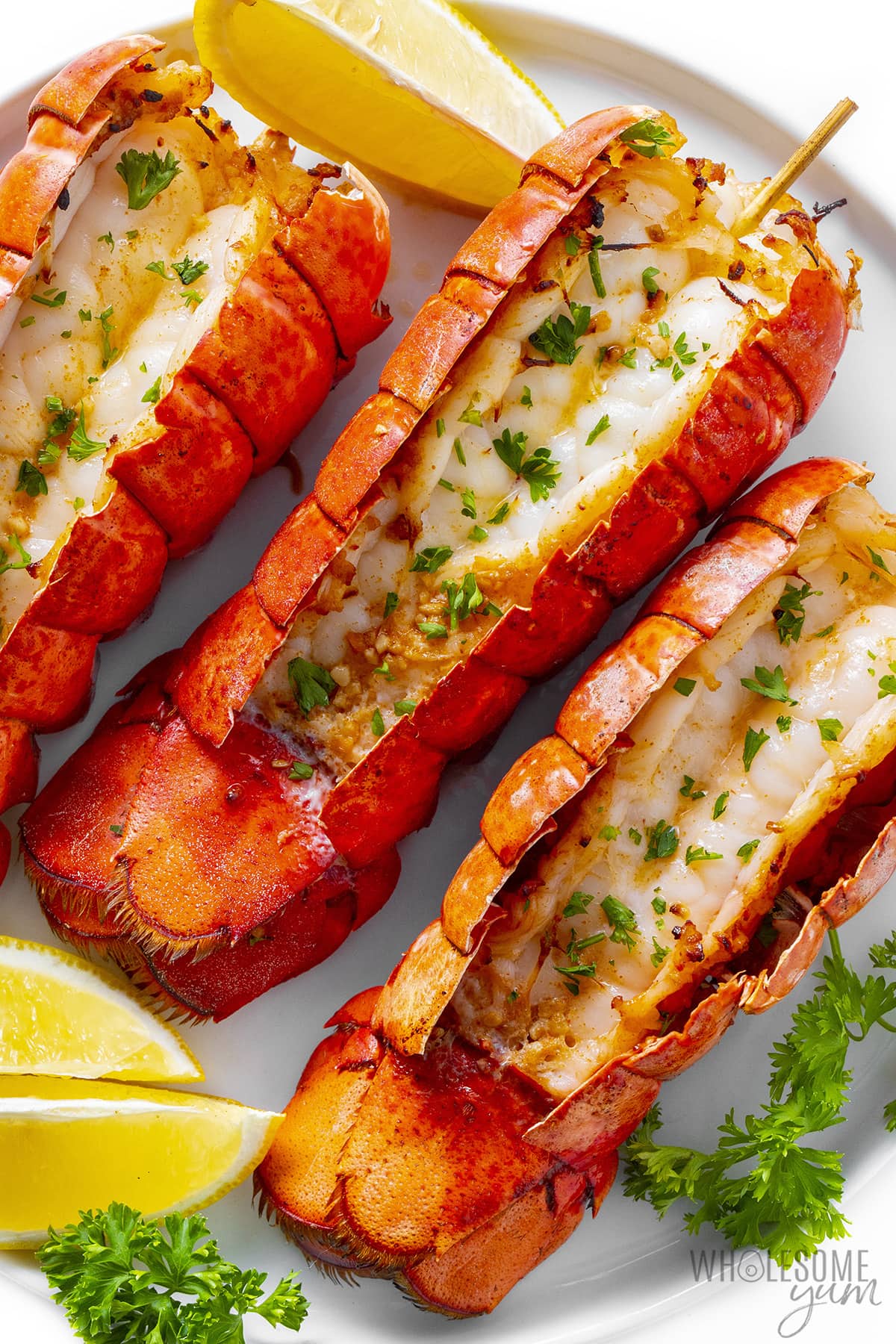 Air fryer lobster tail with lemon wedges.