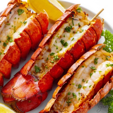 Air fryer lobster tail with a lemon wedge.
