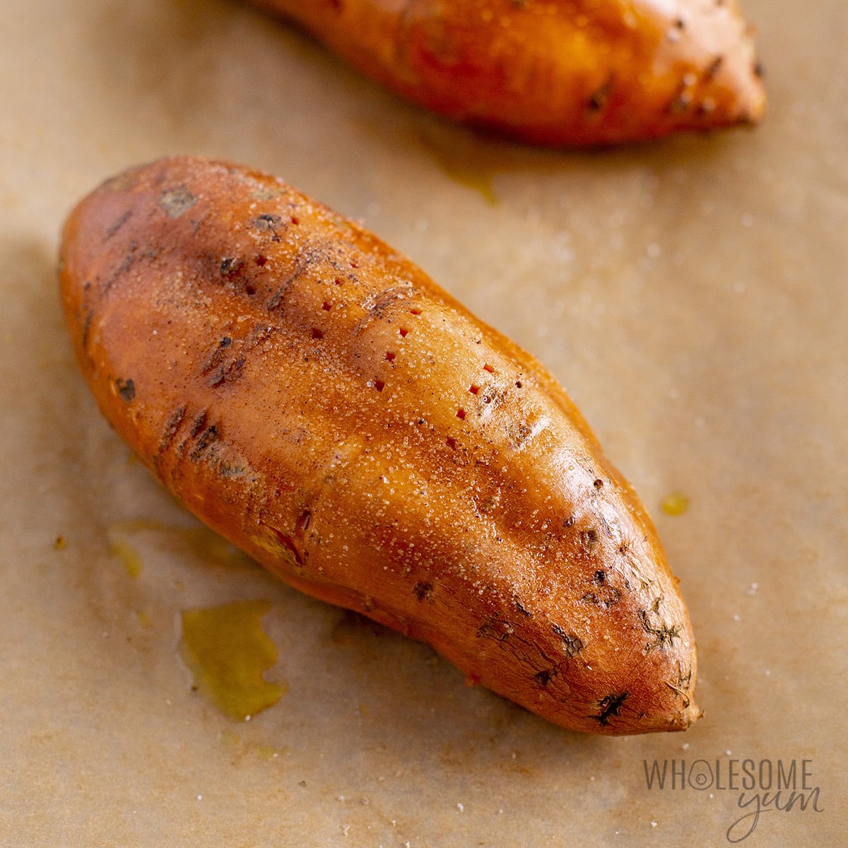 One pierced sweet potato seasoned with oil, salt, and pepper on a baking pan.