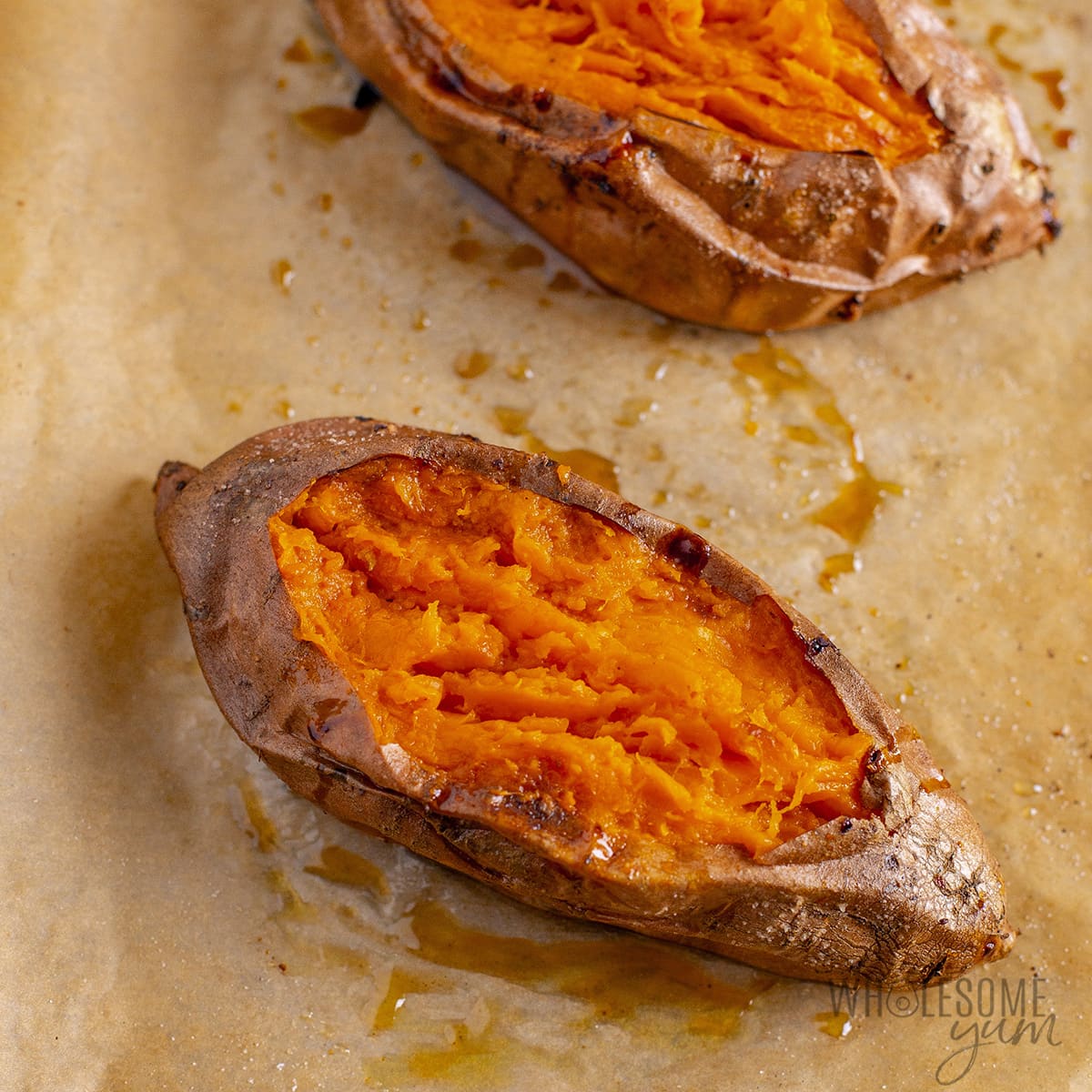 Cooked sweet potatoes sliced open on a baking sheet.