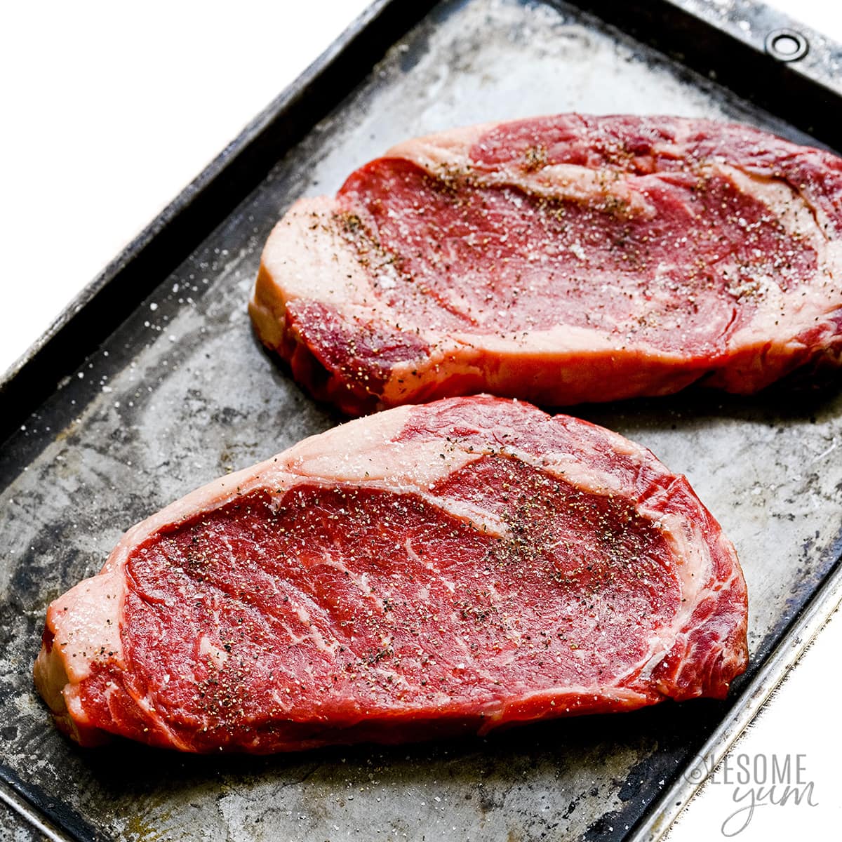 Raw steak seasoned with salt and pepper.