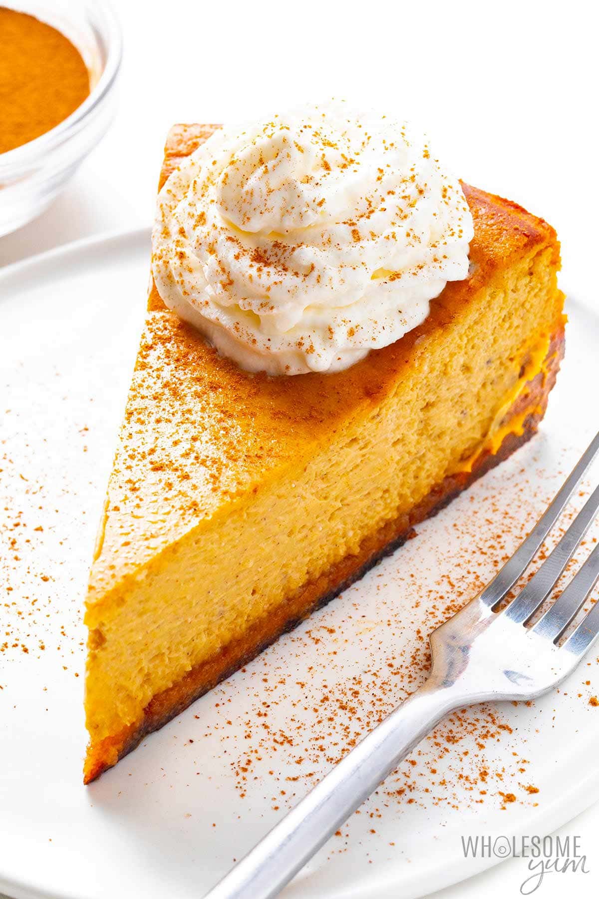 Slice of sugar-free pumpkin cheesecake on a plate with a fork.