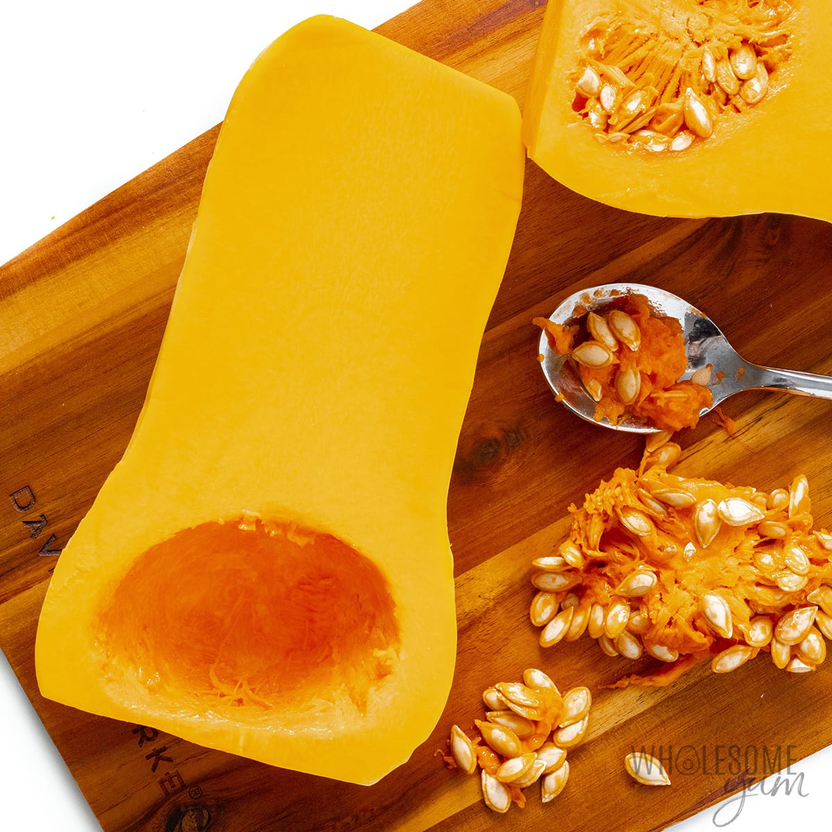 Removing seeds from butternut squash halves.