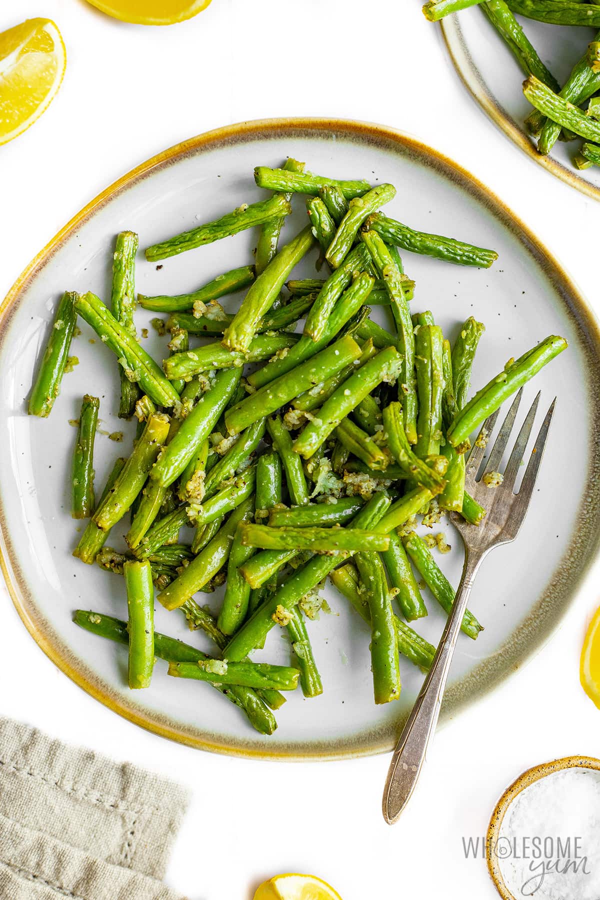 Cooked green beans on a plate with a fork.