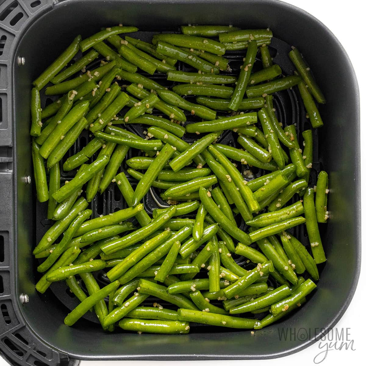 Seasoned green beans in the fryer basket before being cooked.