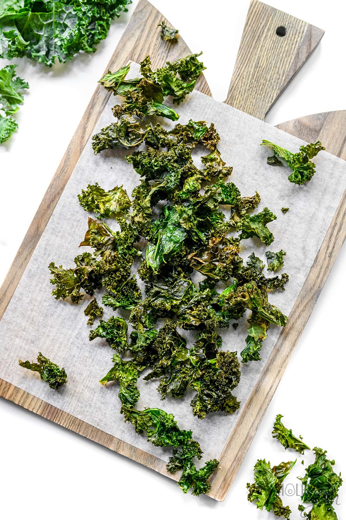 Air fryer kale chips spread out on a cutting board.