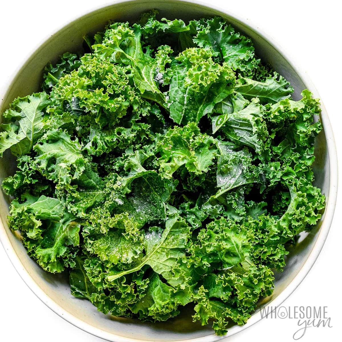 Fresh kale in a bowl with seasonings.