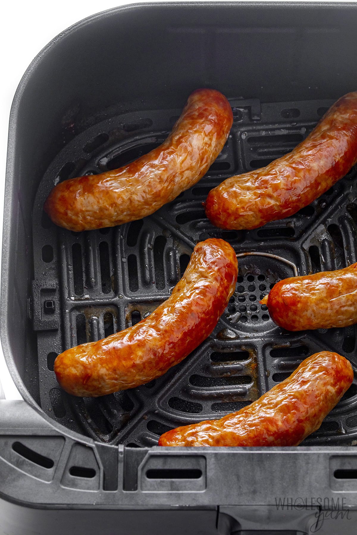 Sausage in air fryer basket.