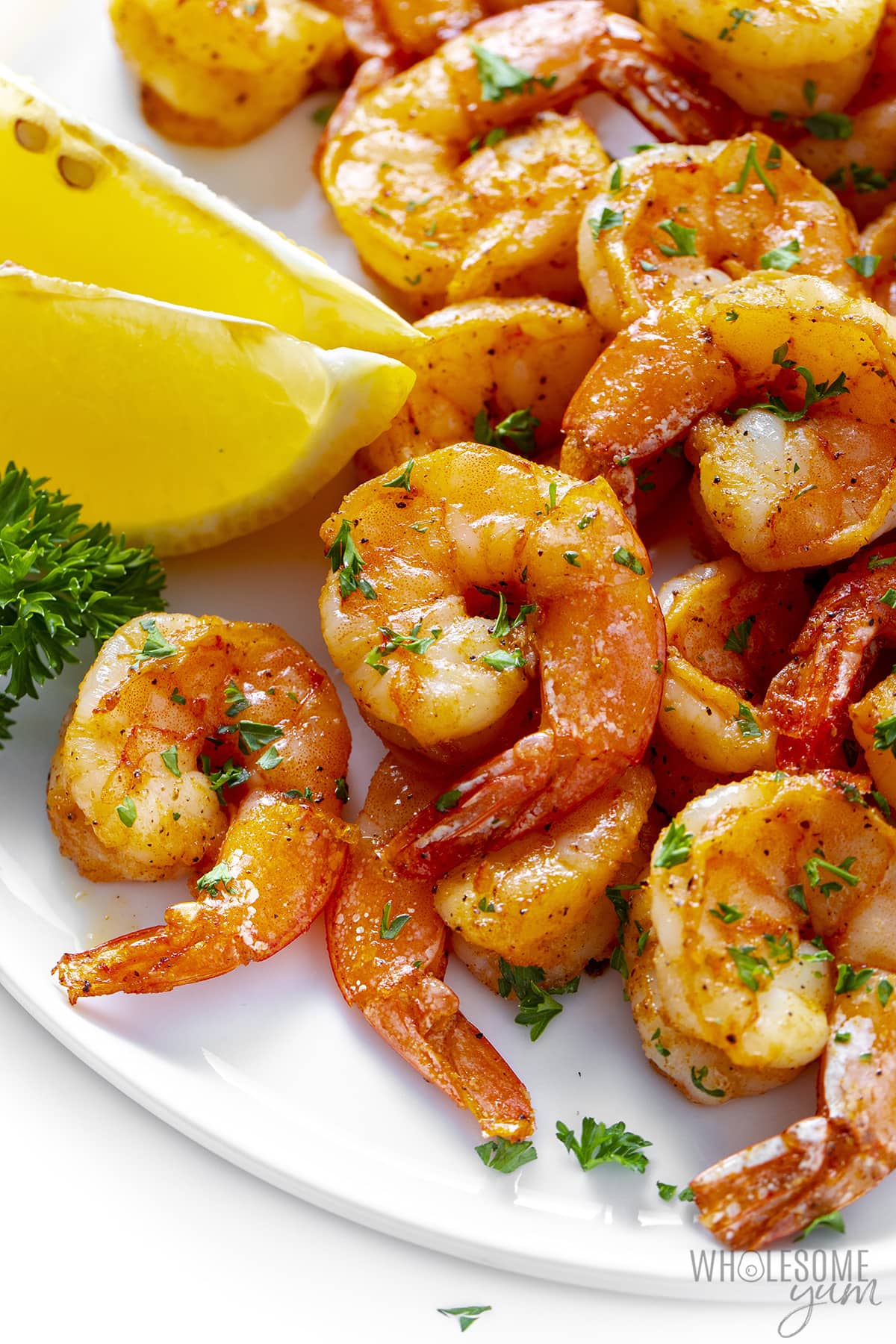 Air fryer shrimp on a plate with a wedge of lemon.