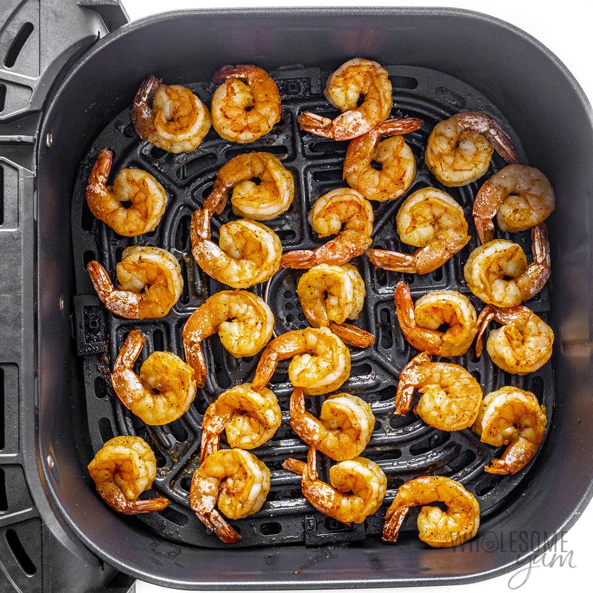 Cooked shrimp in air fryer basket.