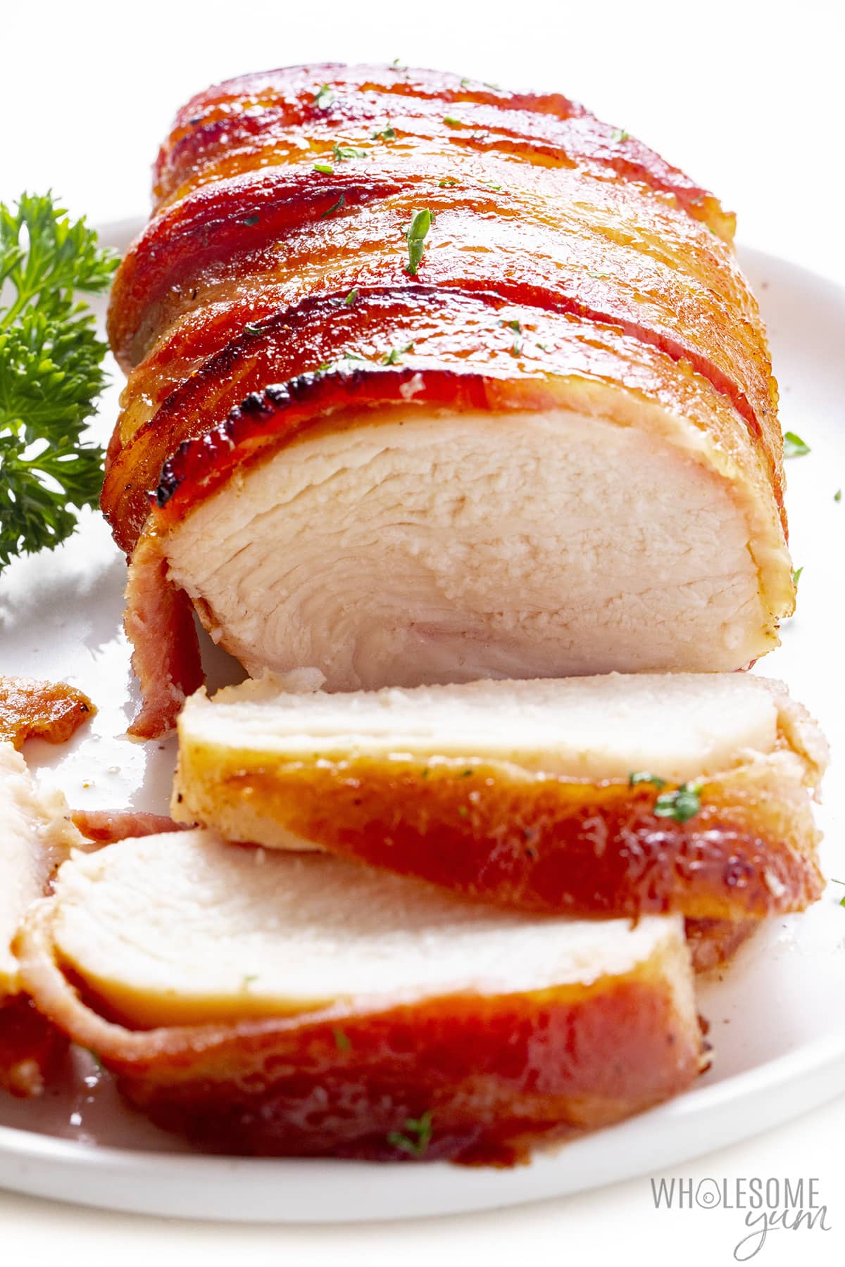 Bacon wrapped chicken sliced on a plate.