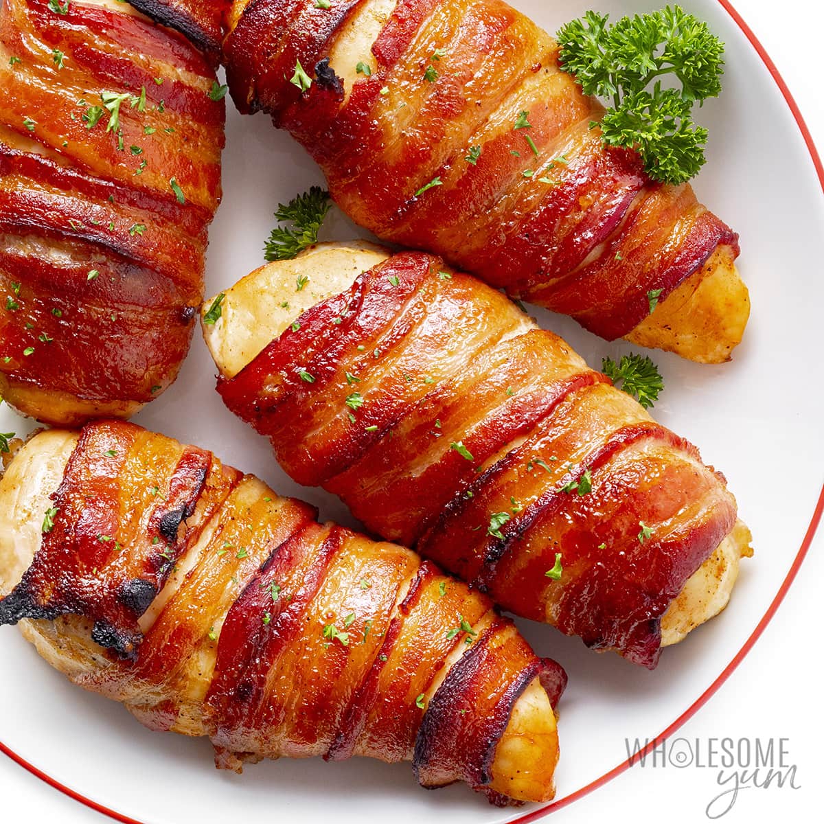 Baked bacon wrapped chicken breasts sprinkled with parsley.