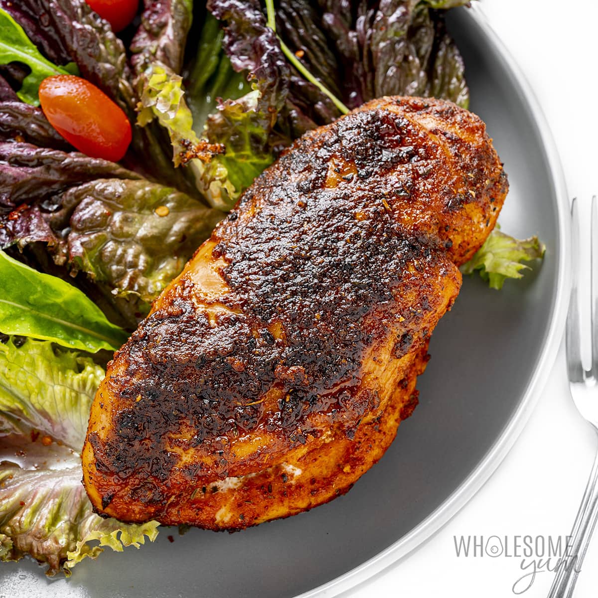 Blackened chicken on a plate with salad.