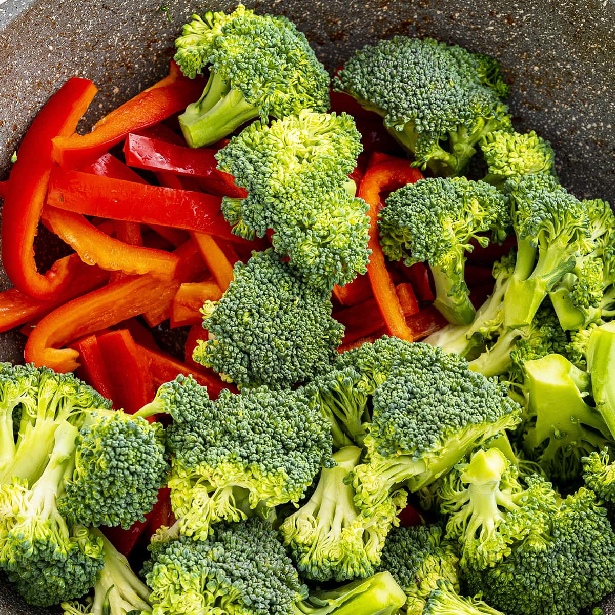Se añaden brócoli y pimientos rojos al wok.