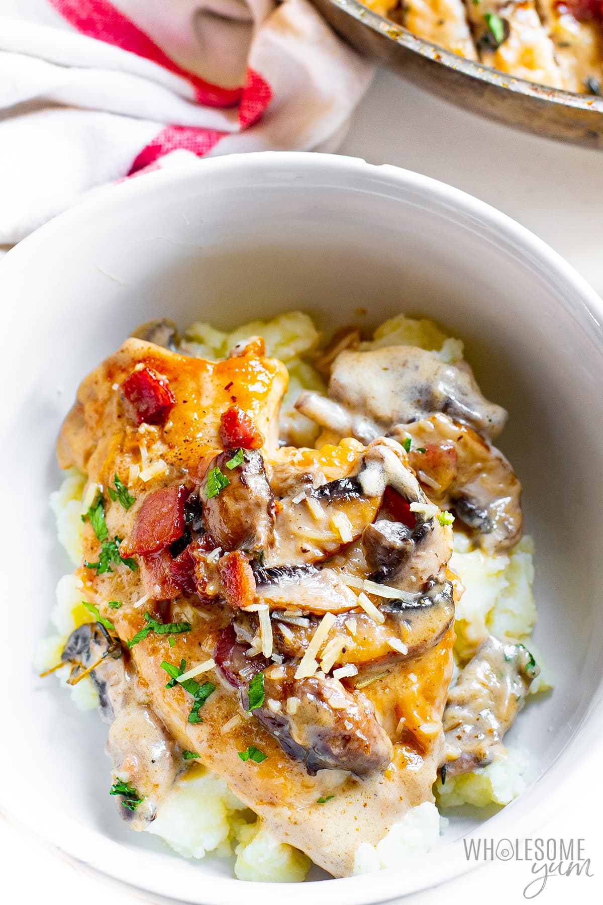 Chicken and mushrooms in a bowl over mashed potatoes.
