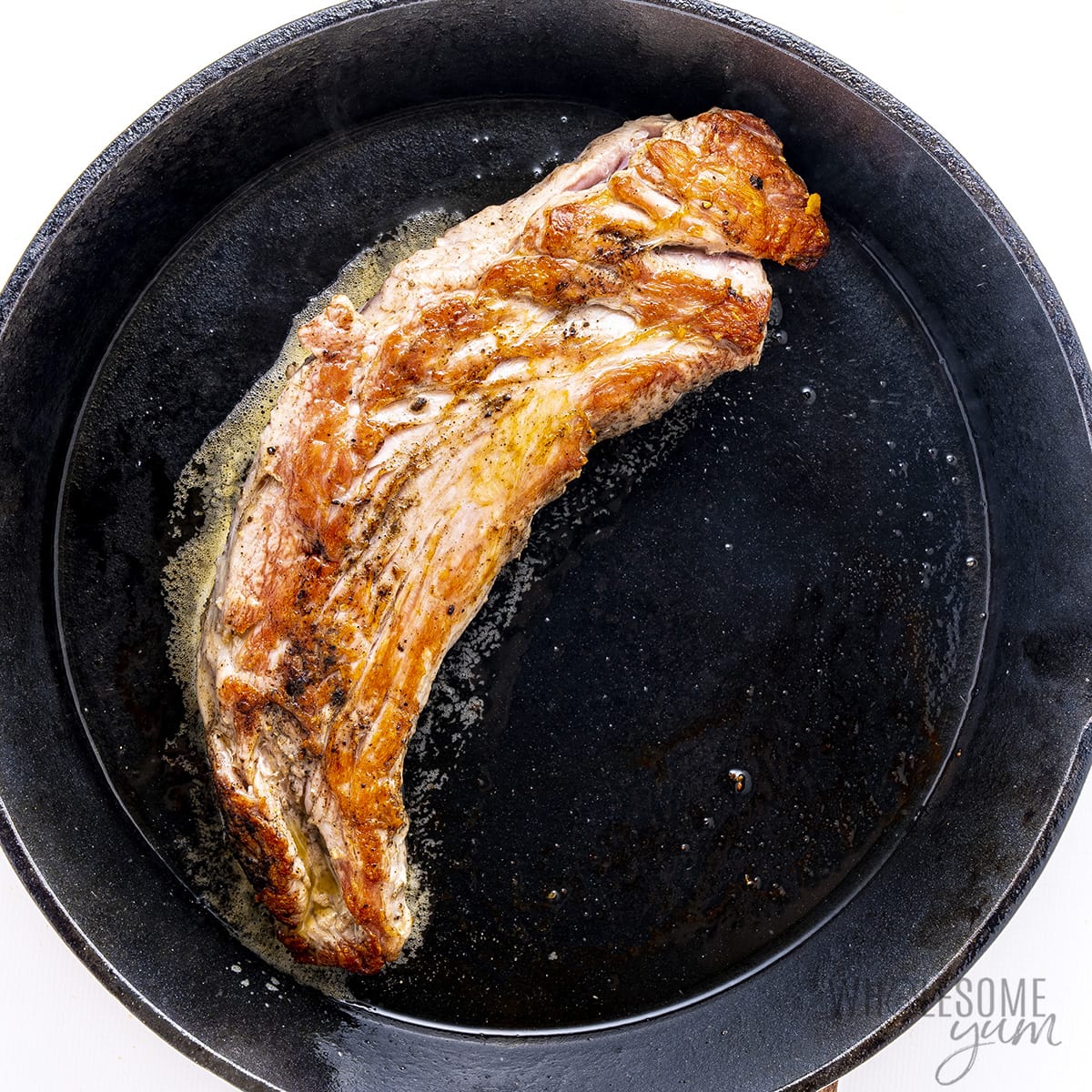 Pork tenderloin seared on a cast iron skillet. 