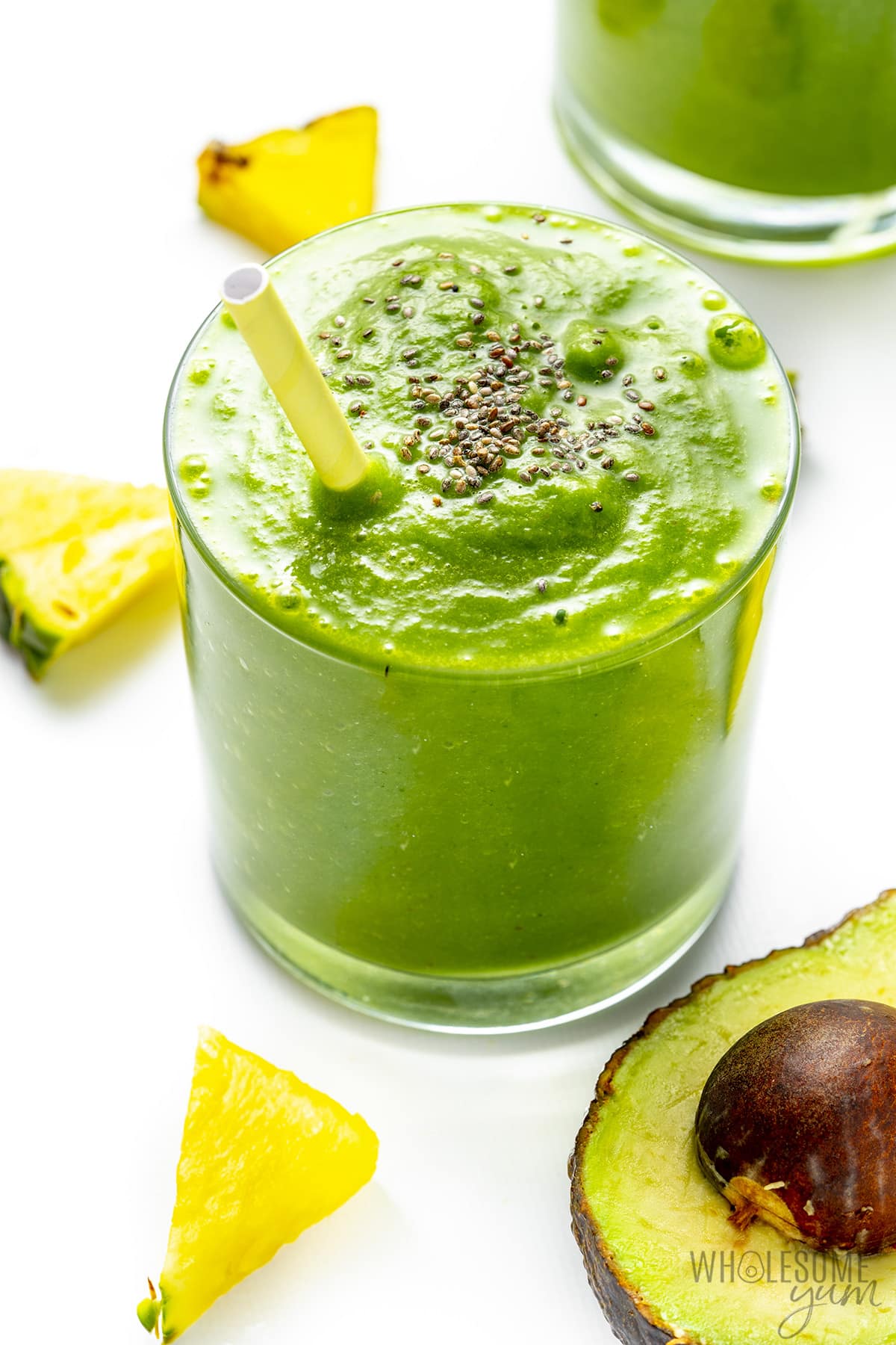 Green detox smoothie with a straw and chia seeds on top.