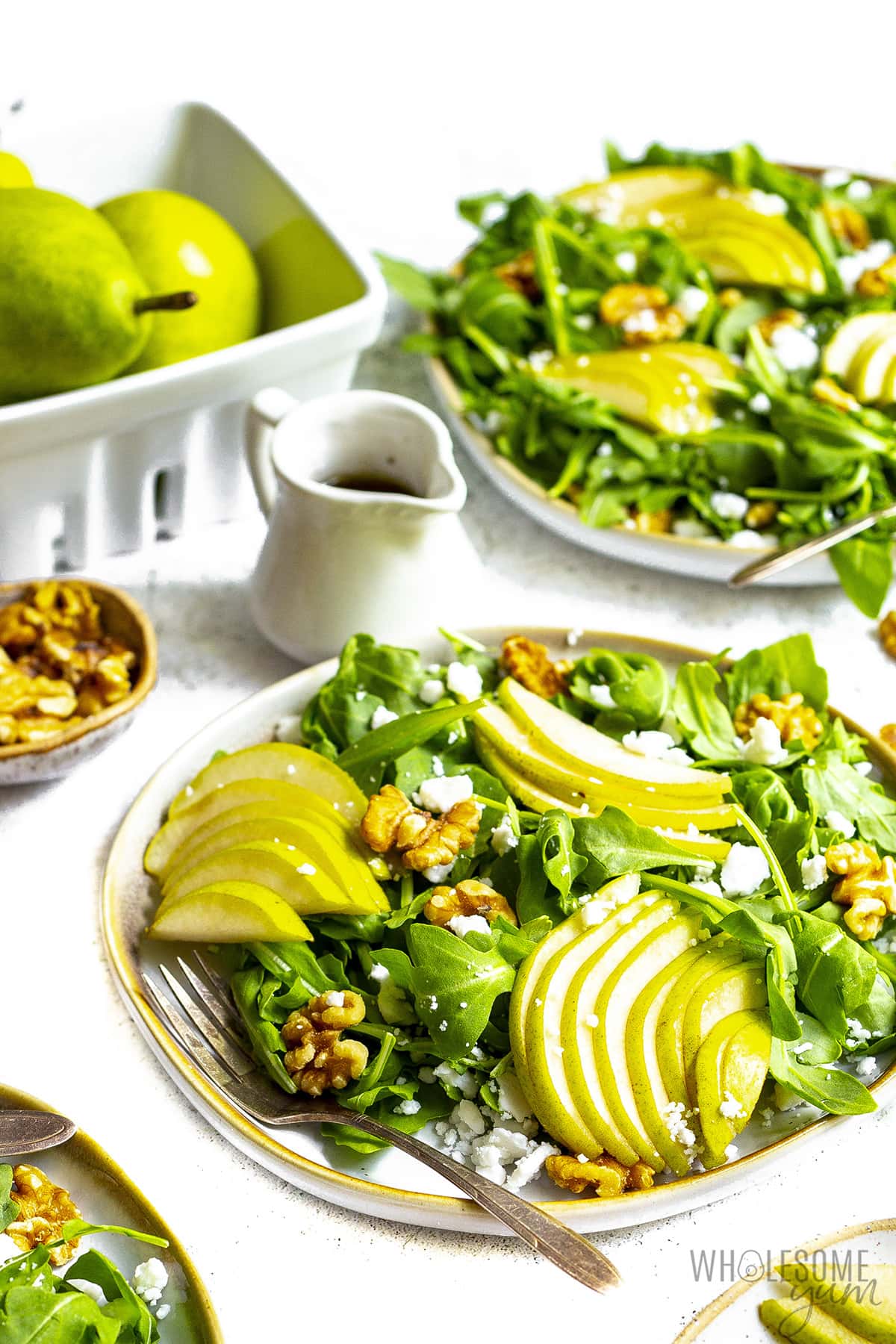 Salad with pears, with dressing and more pears in the background.