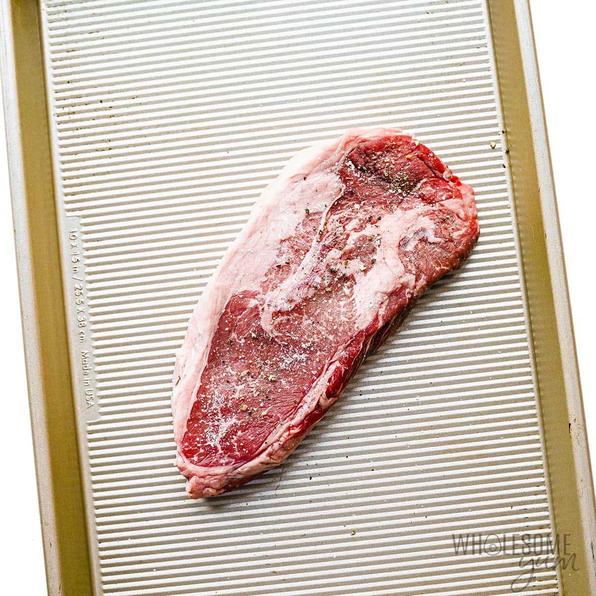 Seasoned steak on a sheet pan. 