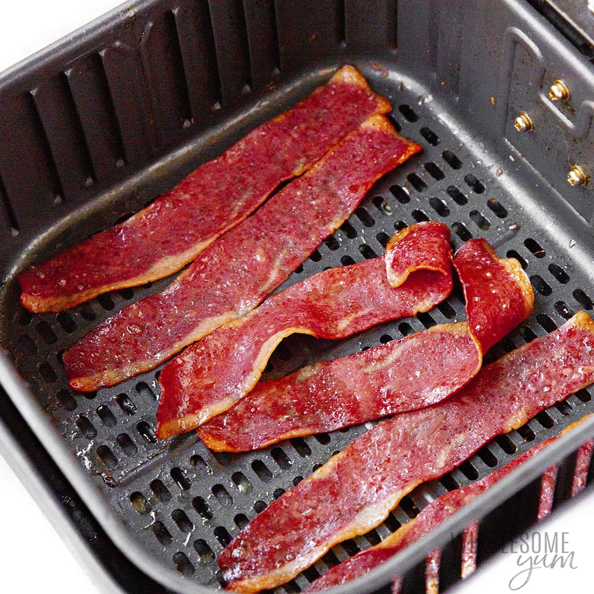 Cooked turkey bacon in air fryer basket.