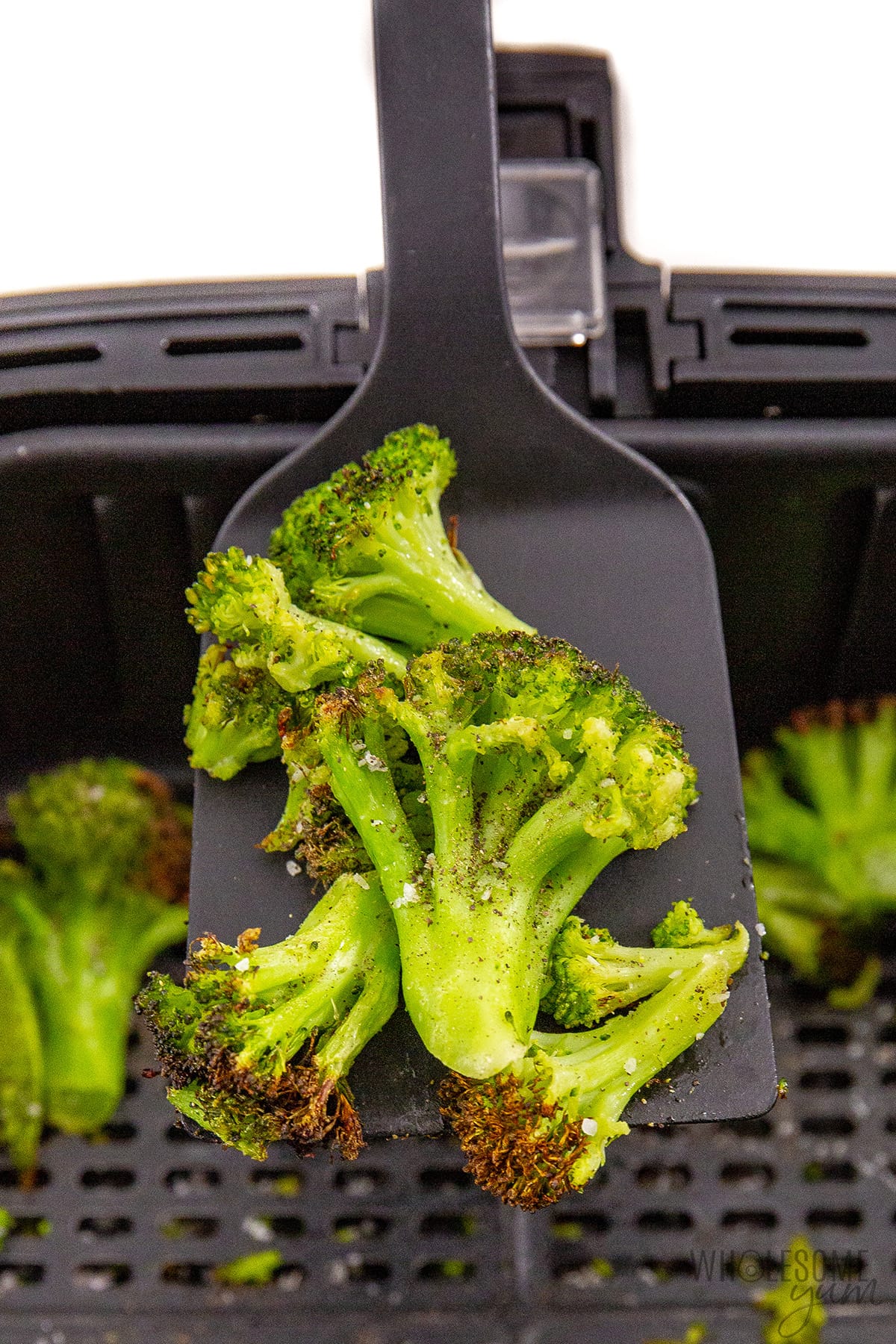 Air fried frozen broccoli on a spatula.