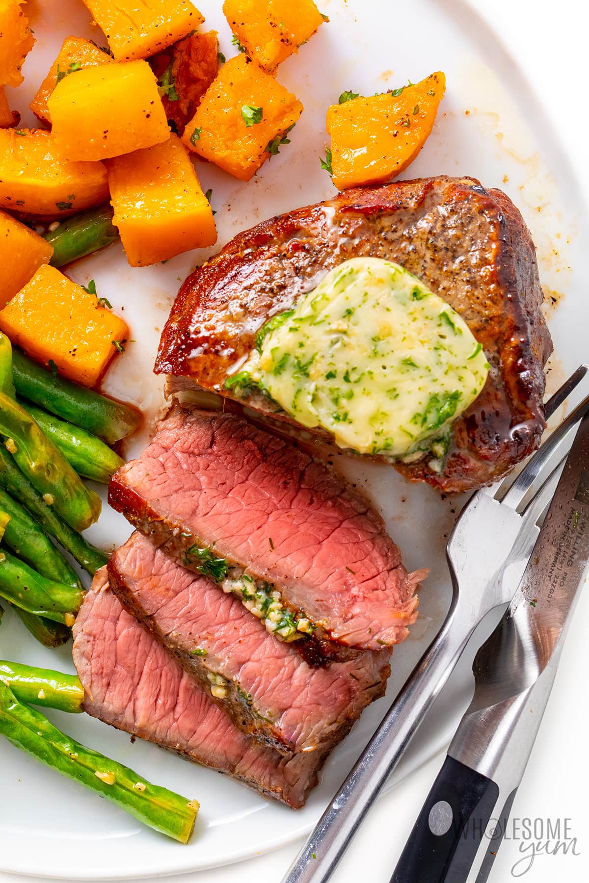 Air fryer steak next to roasted butternut squash and green beans on a plate.