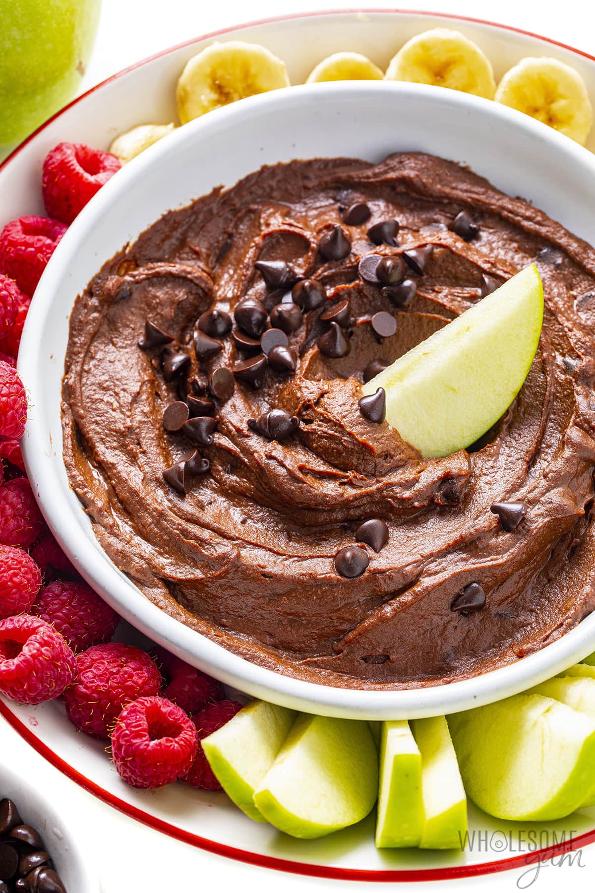 Dark chocolate hummus in a bowl with a green apple wedge.