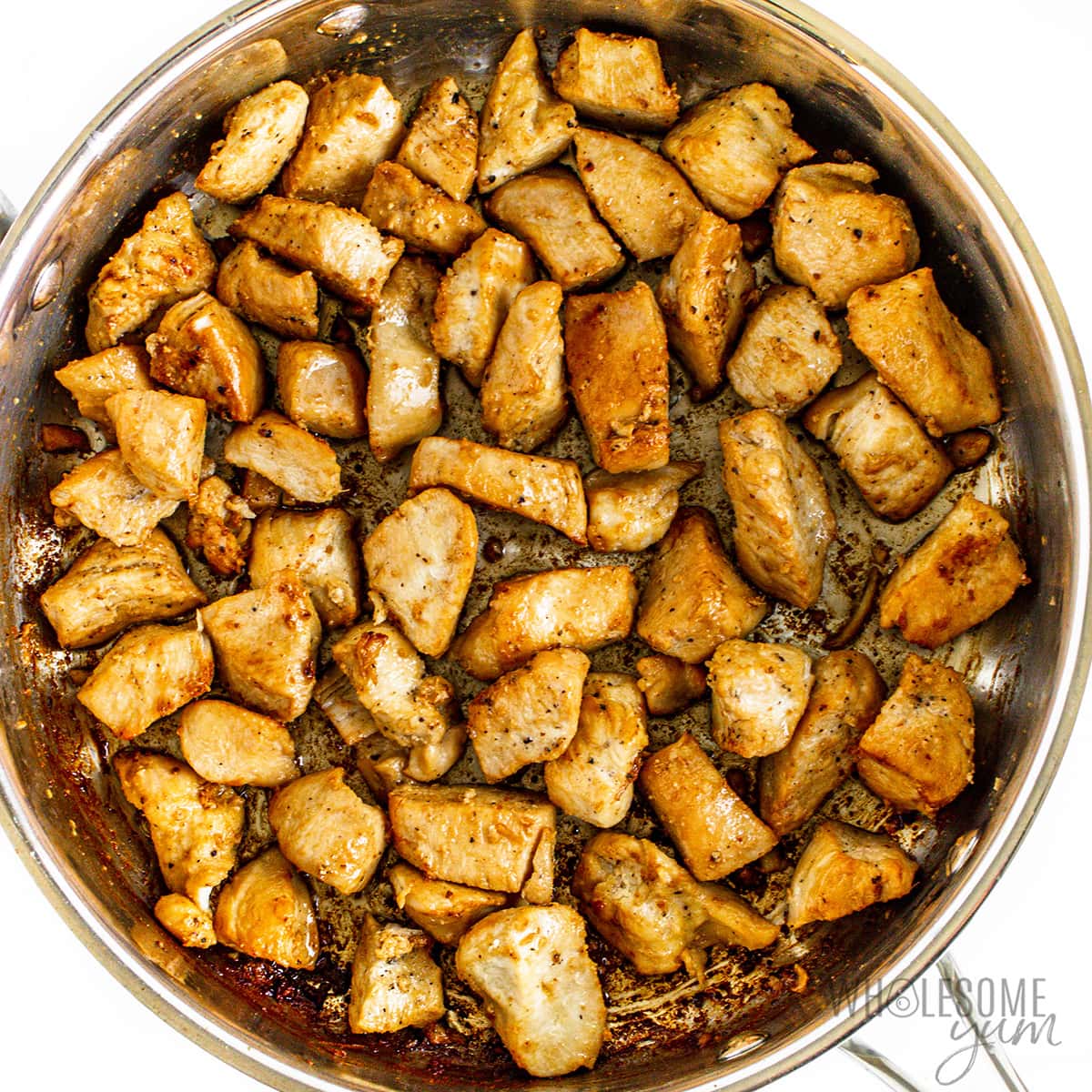 Cooked chicken cubes in a skillet. 