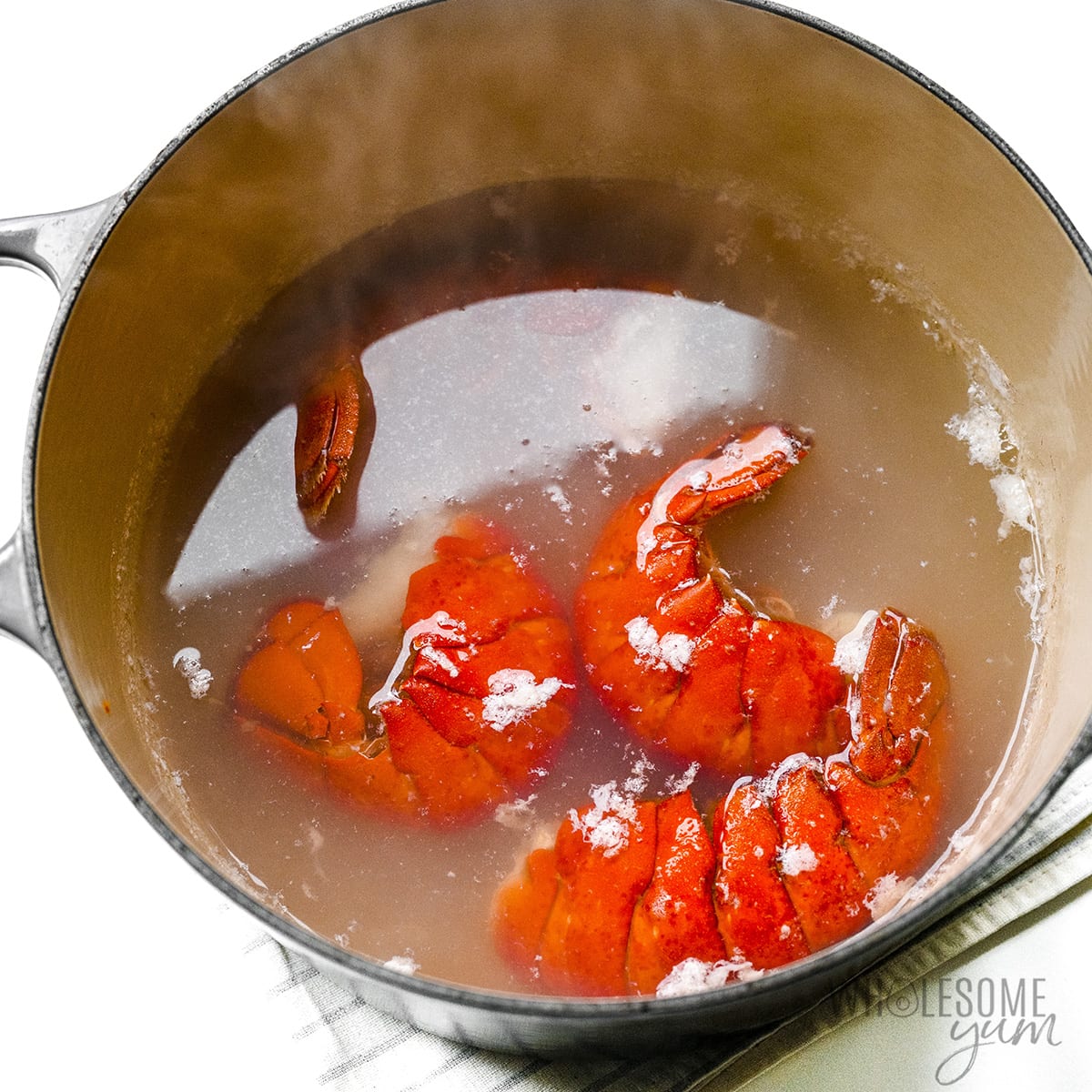 Water in a large pot with lobster tails.
