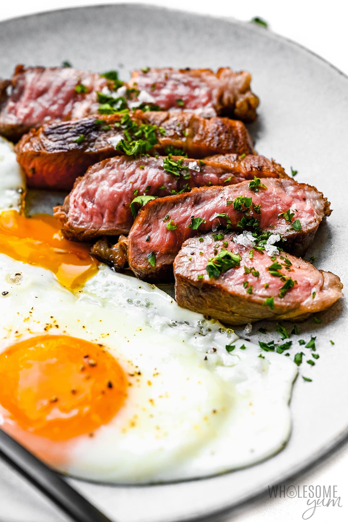 Sliced steak and eggs on a plate.