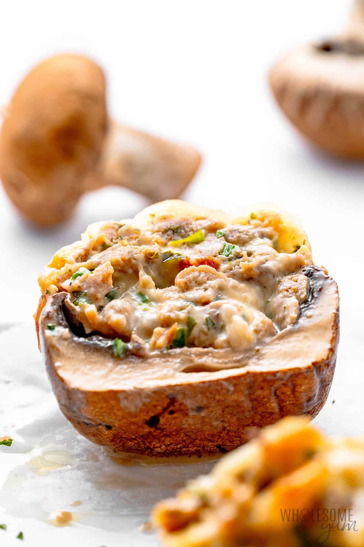 Creamy sausage stuffed mushrooms cut in half to show the filling.
