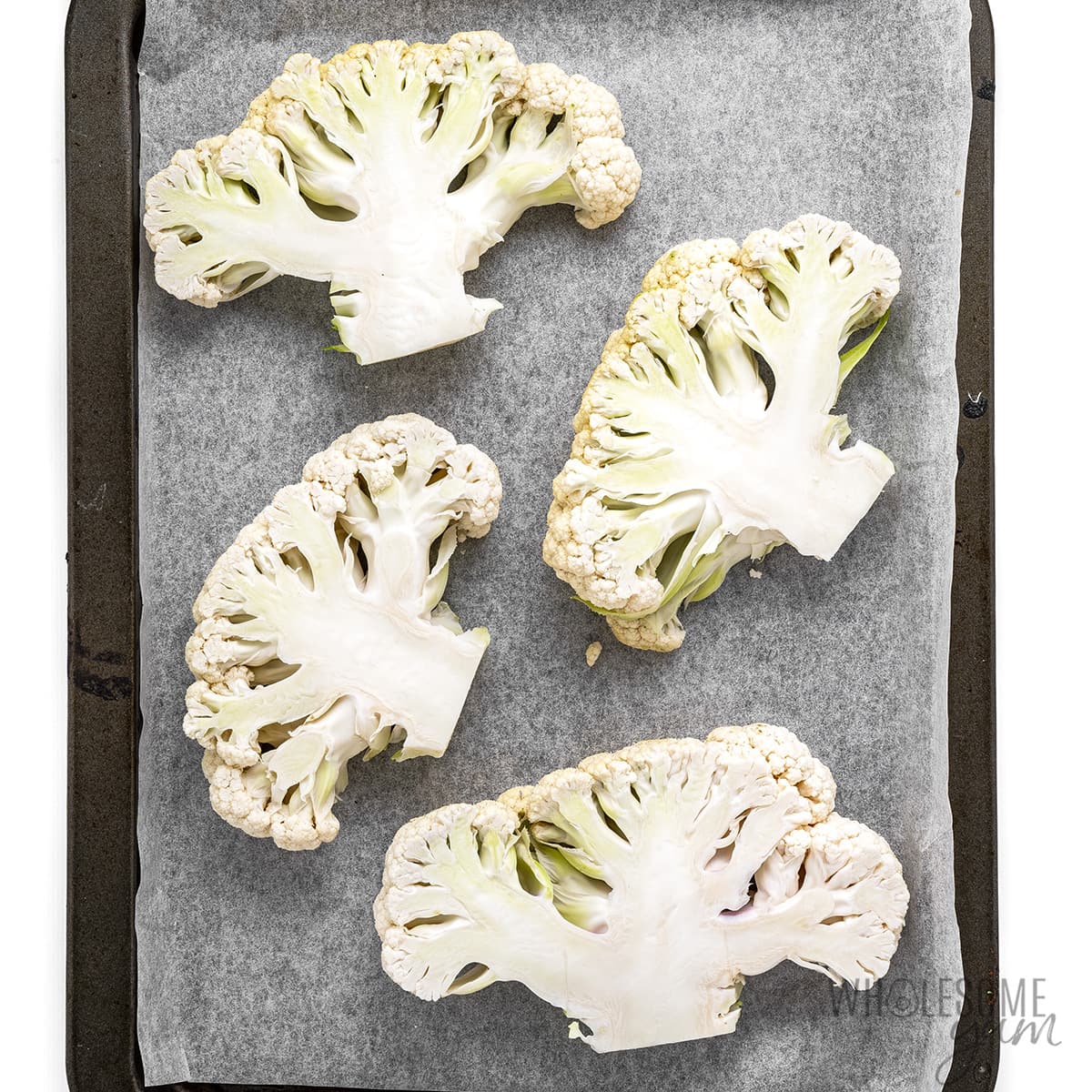 Sliced cauliflower on a baking sheet.