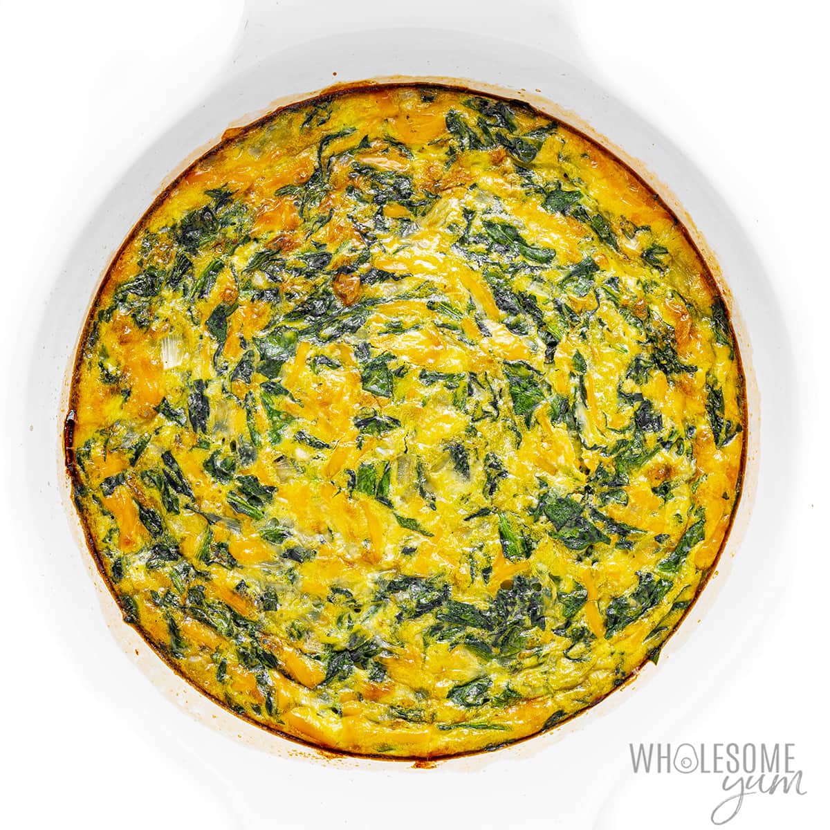Baked crustless spinach quiche in baking dish.