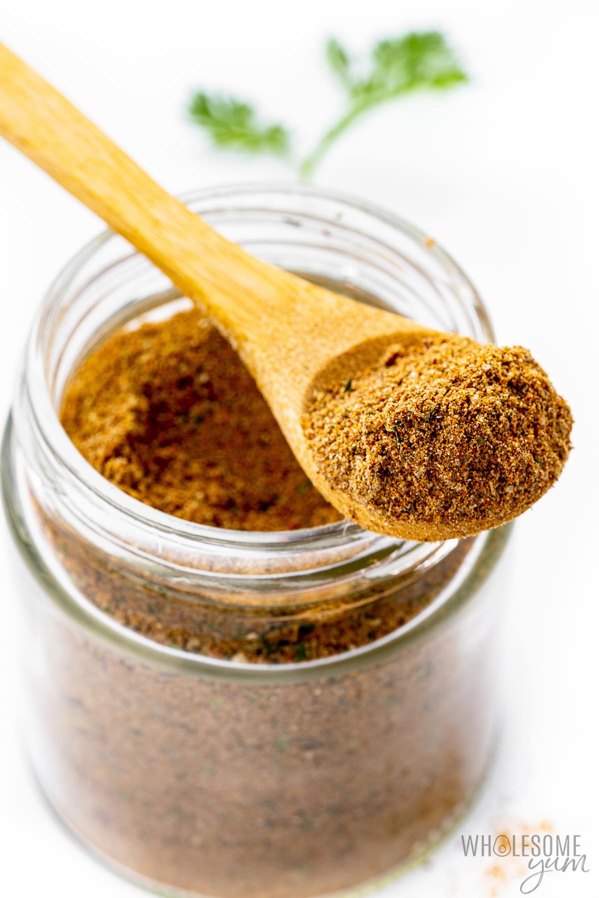 Jerk seasoning in a jar and on a wooden spoon.