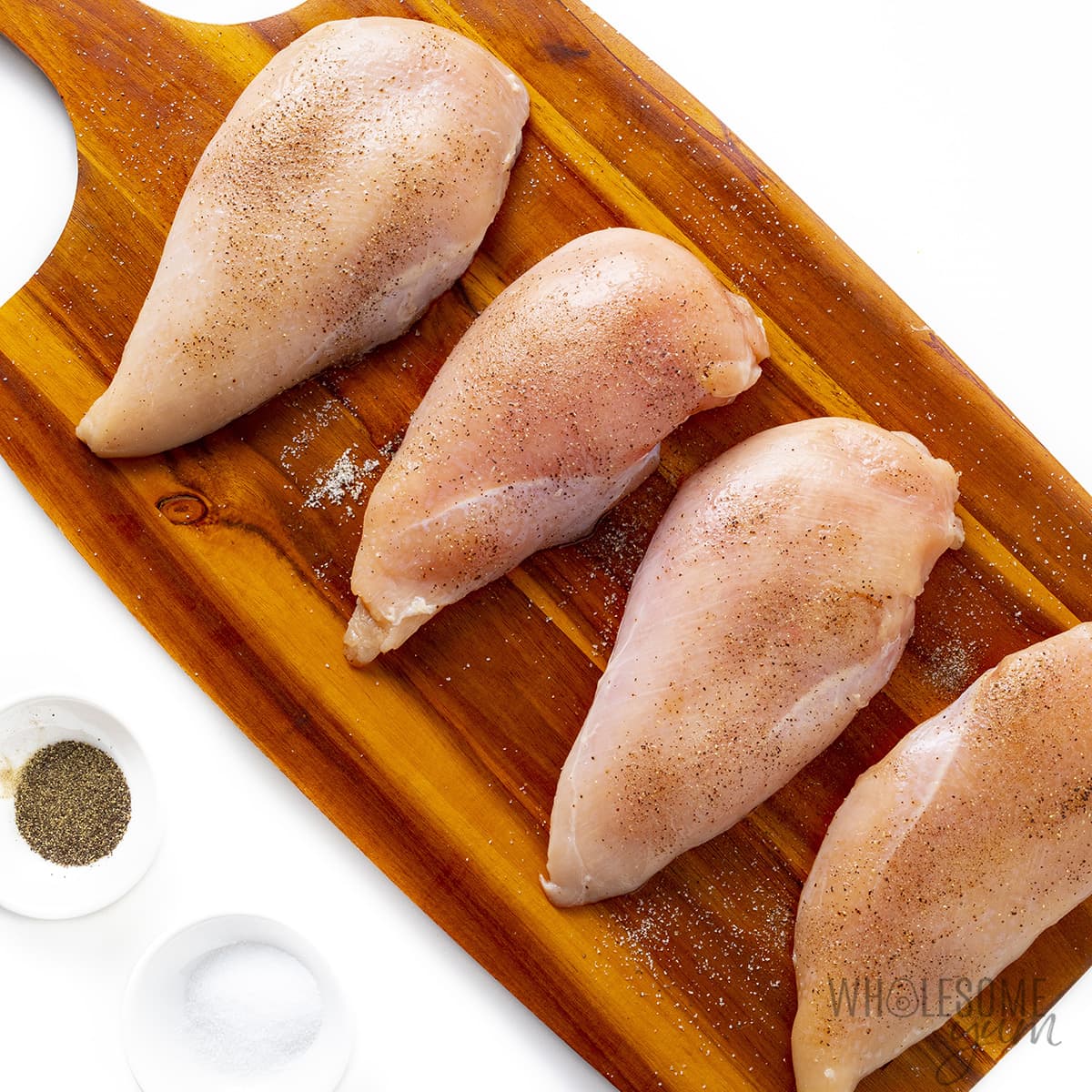 Raw chicken breasts on a cutting board.