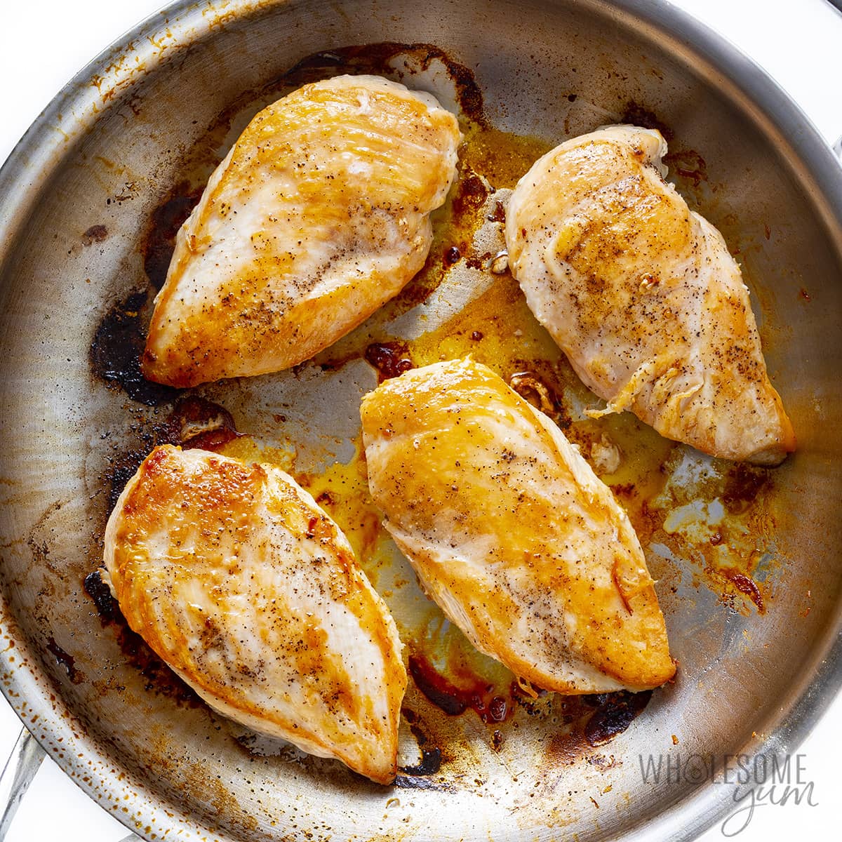 Chicken breasts seared in skillet.
