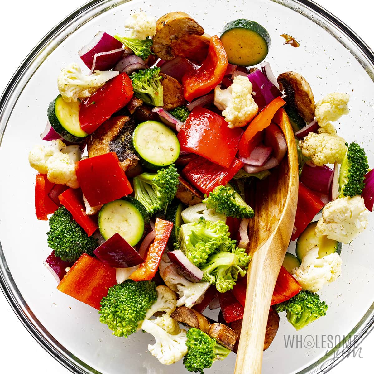 Veggies tossed in olive oil and seasoning in a bowl.