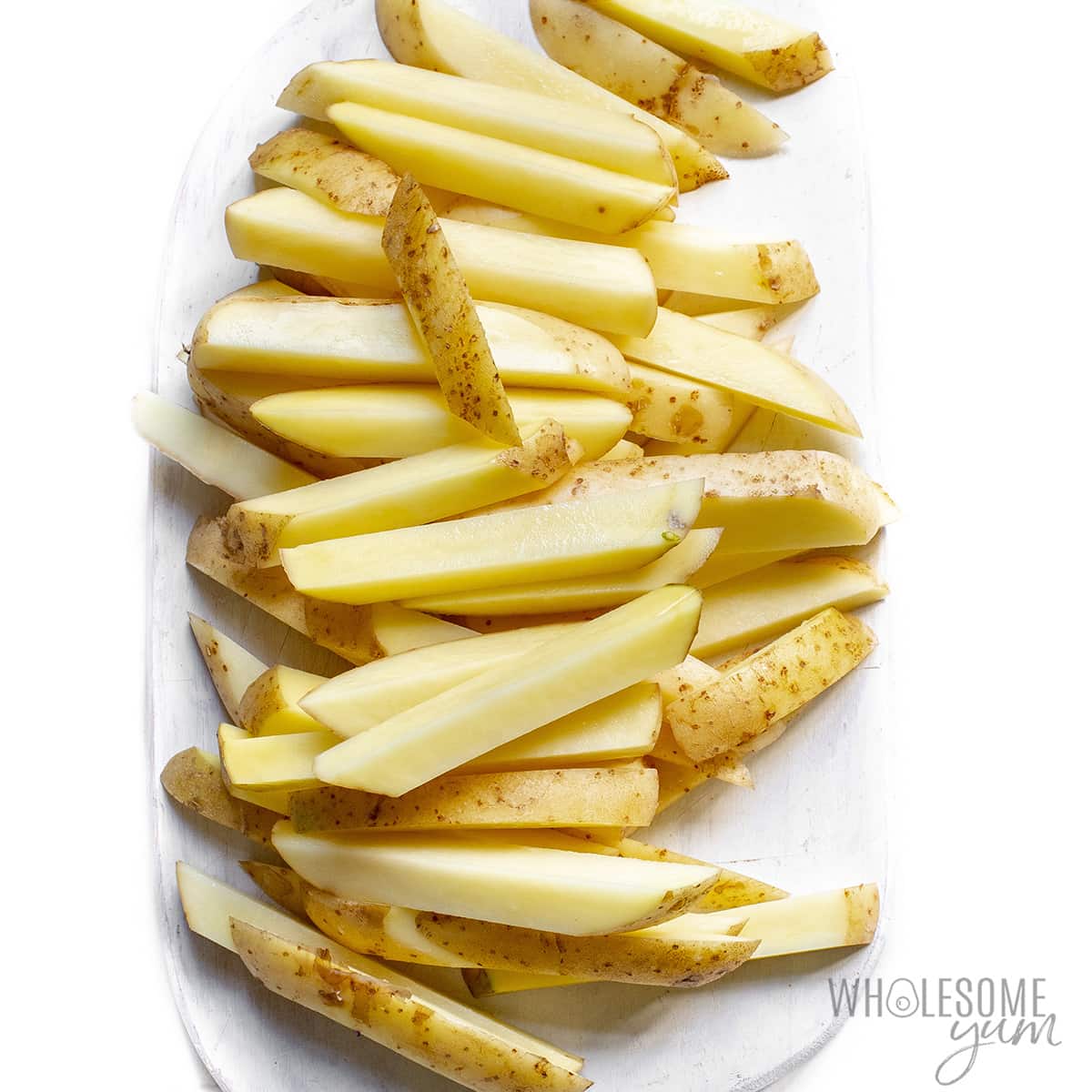 Potatoes sliced into strips on a plate.