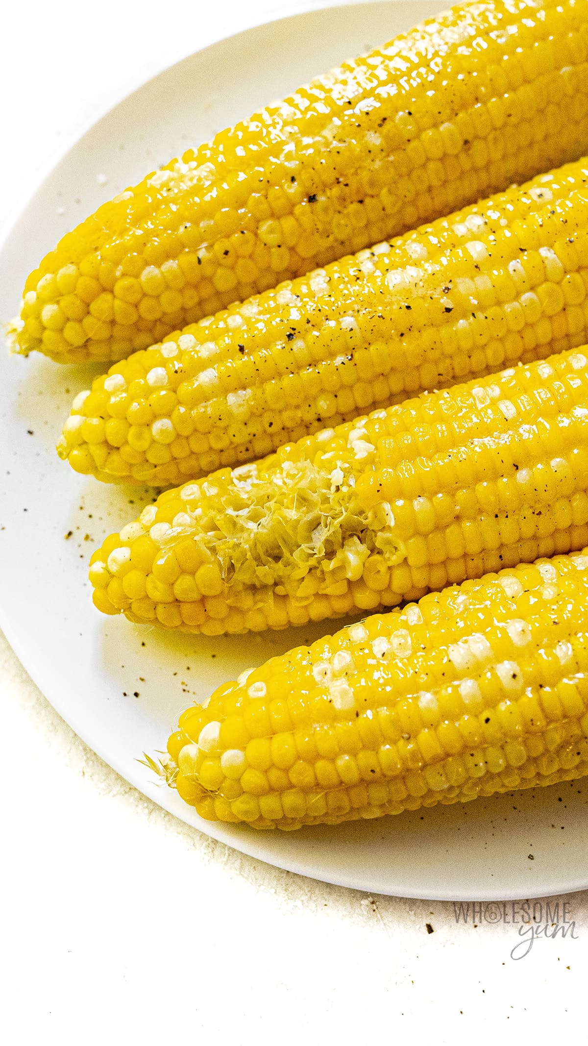 Corn on a plate with a bite taken out of one cob.