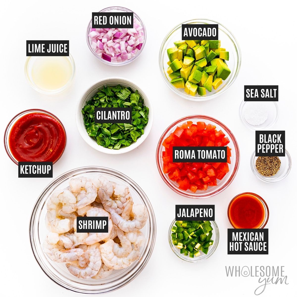 Bowl of shrimp next to tomatoes, cilantro, avocado, red onions, and other sauce ingredients in small bowls with labels.