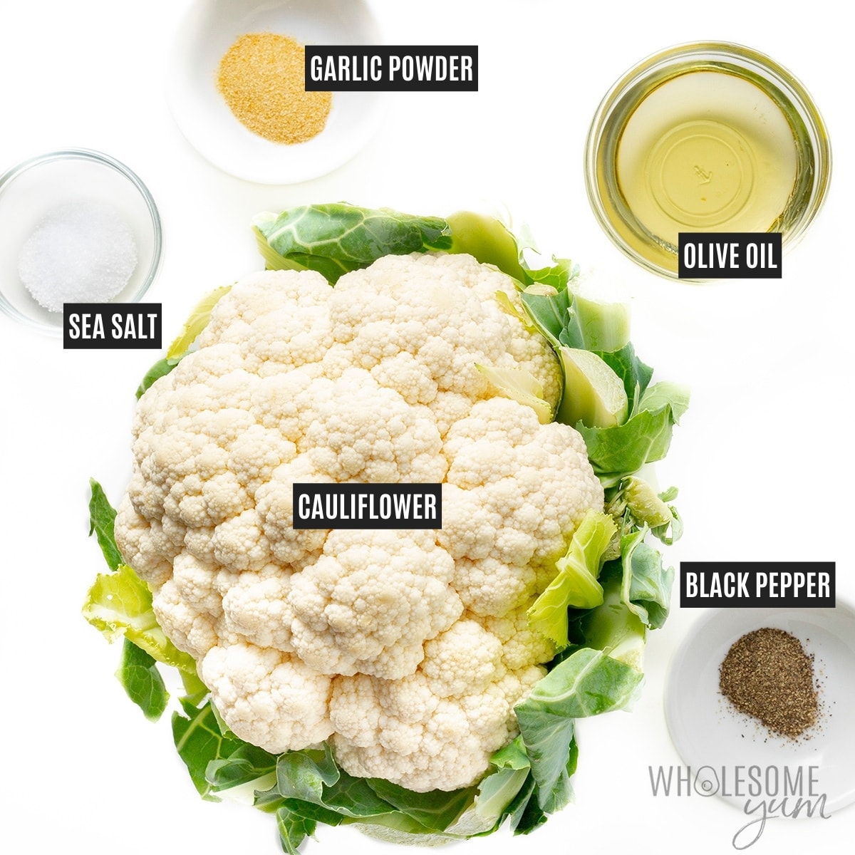 Head of cauliflower surrounded by oil and seasonings in small bowls.