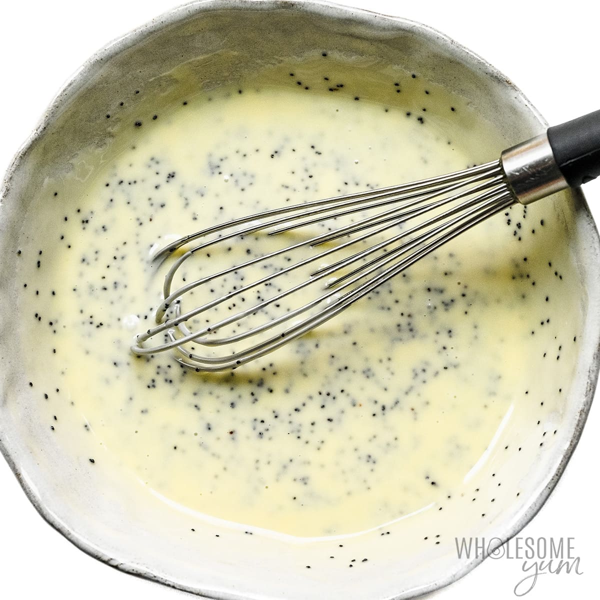 Poppy seed salad dressing whisked in a bowl.