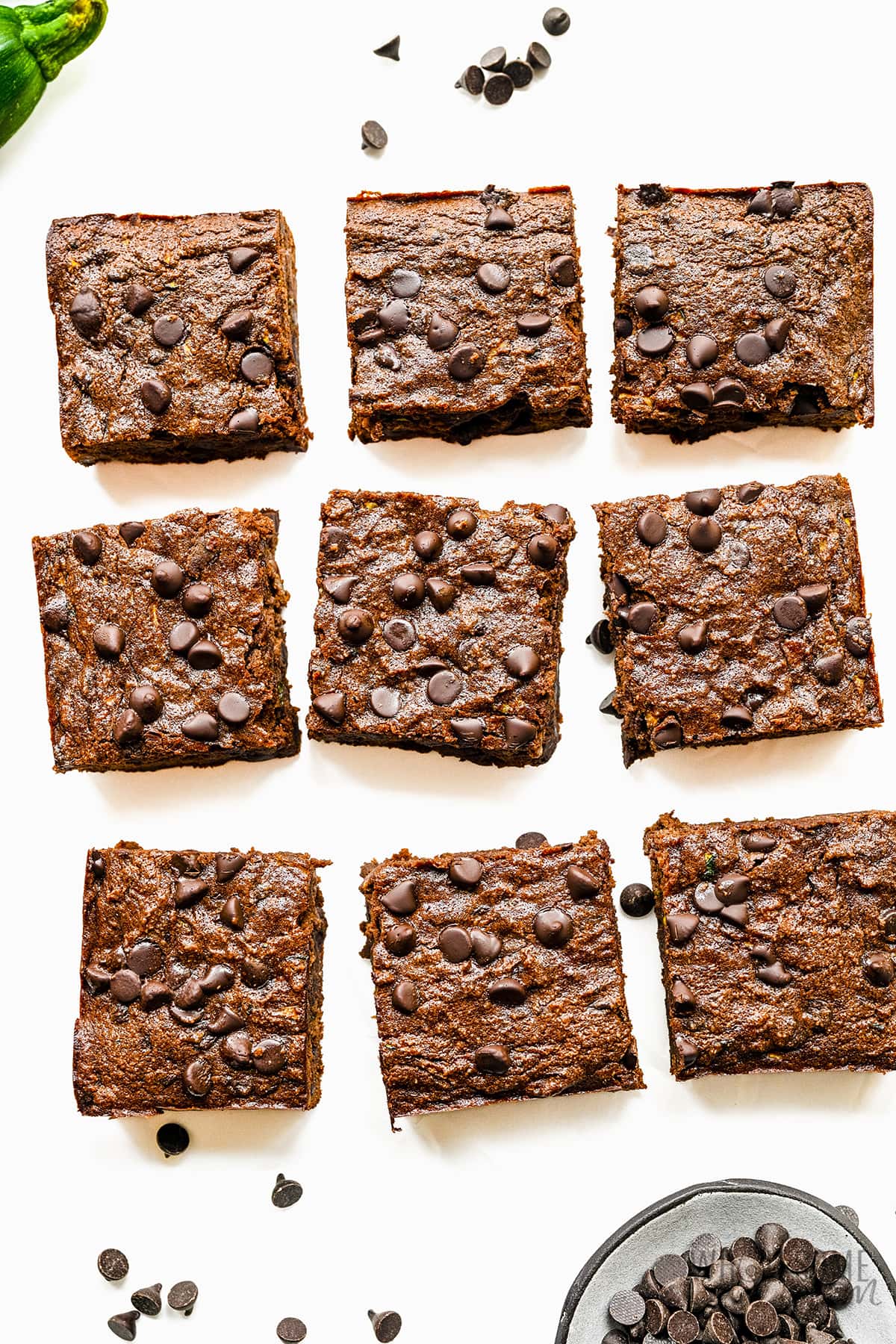 Zucchini brownies cut into squares on a white surface.