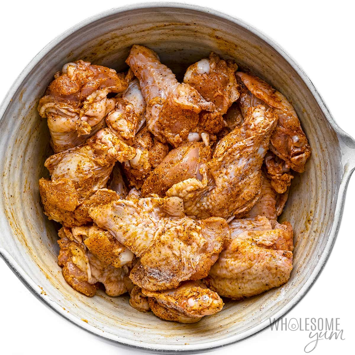 Raw chicken wings seasoned in a bowl.