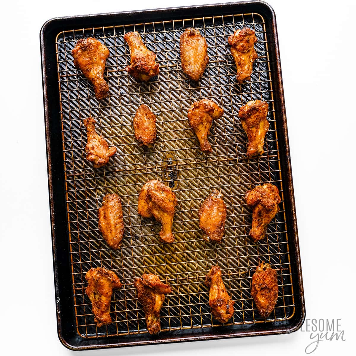 Crispy oven baked chicken wings on a rack over a baking sheet.