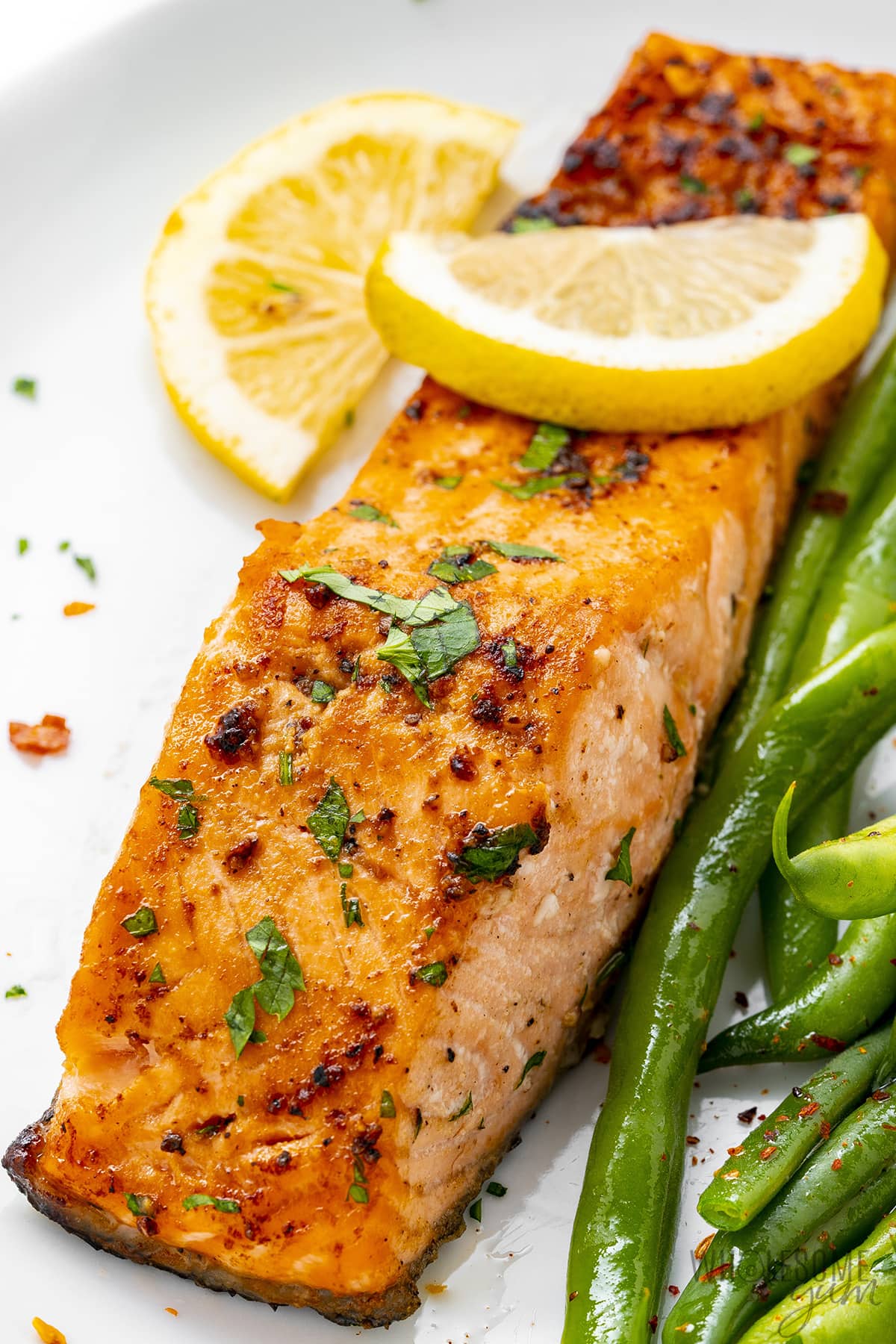 Broiled salmon on a plate with green beans.